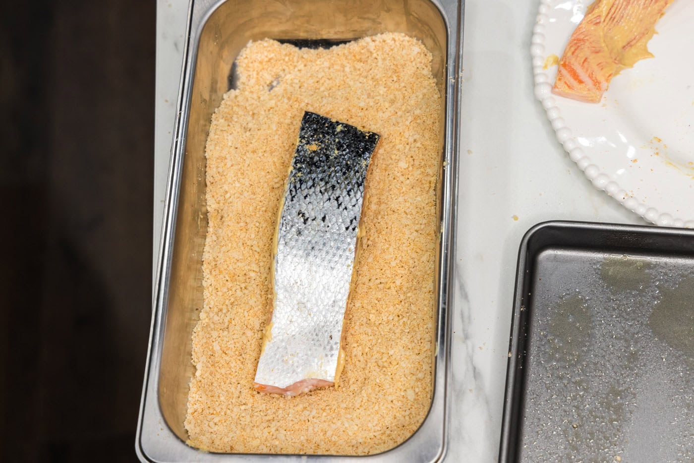 Salmon filets flesh side down in a breading tray or breadcrumbs