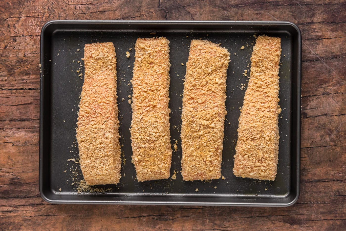 breadcrumb coated salmon filets on a baking sheet