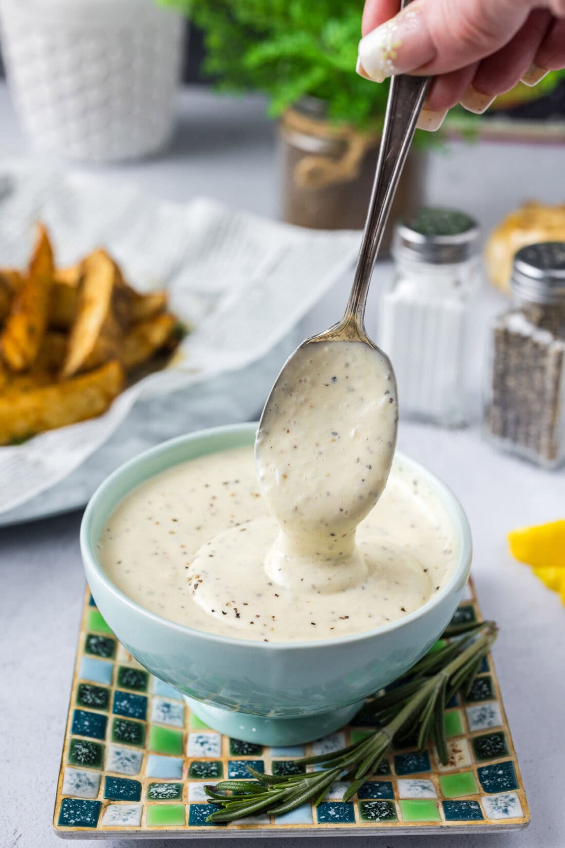 Garlic Aioli falling off a spoon into a bowl of Garlic Aioli