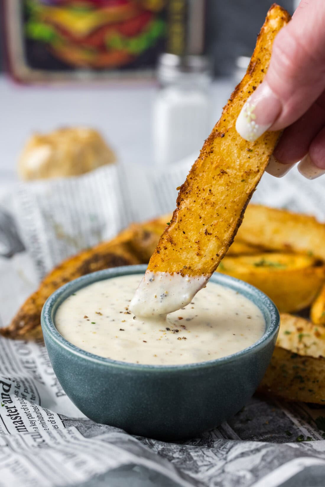 Potato wedge being dipped into Garlic Aioli