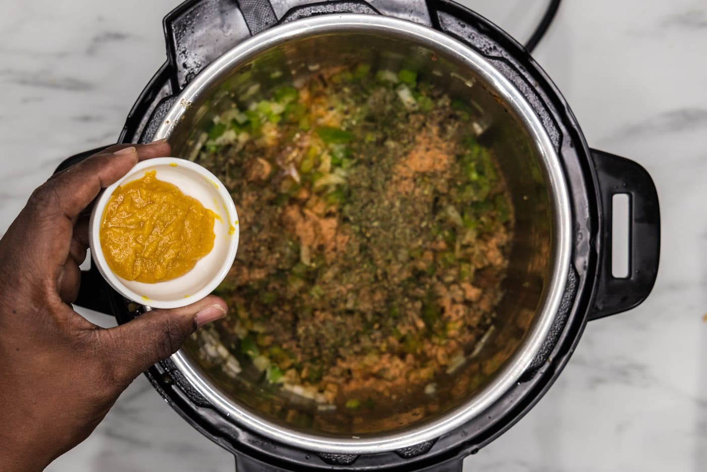 adding seasoning to chopped veggies in an instant pot