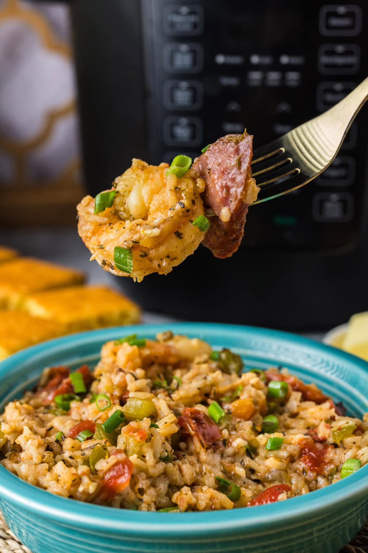 Piece of shrimp and sausage on a fork held above a bowl of Instant Pot Jambalaya