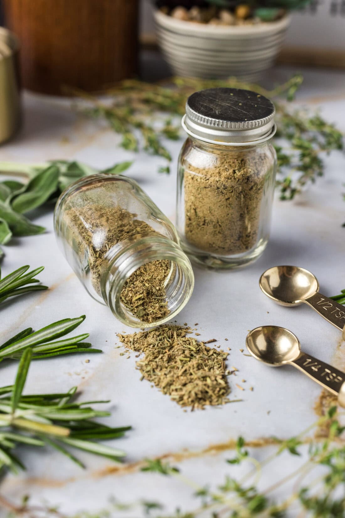 Jar of Poultry Seasoning tipped onto the counter with another jar of Poultry Seasoning behind it