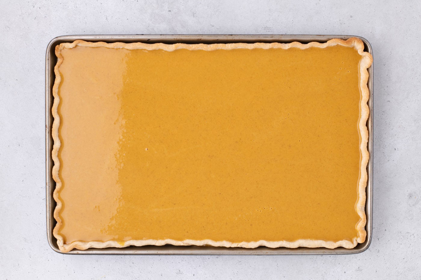 pumpkin pie filling over crust in a jelly roll pan