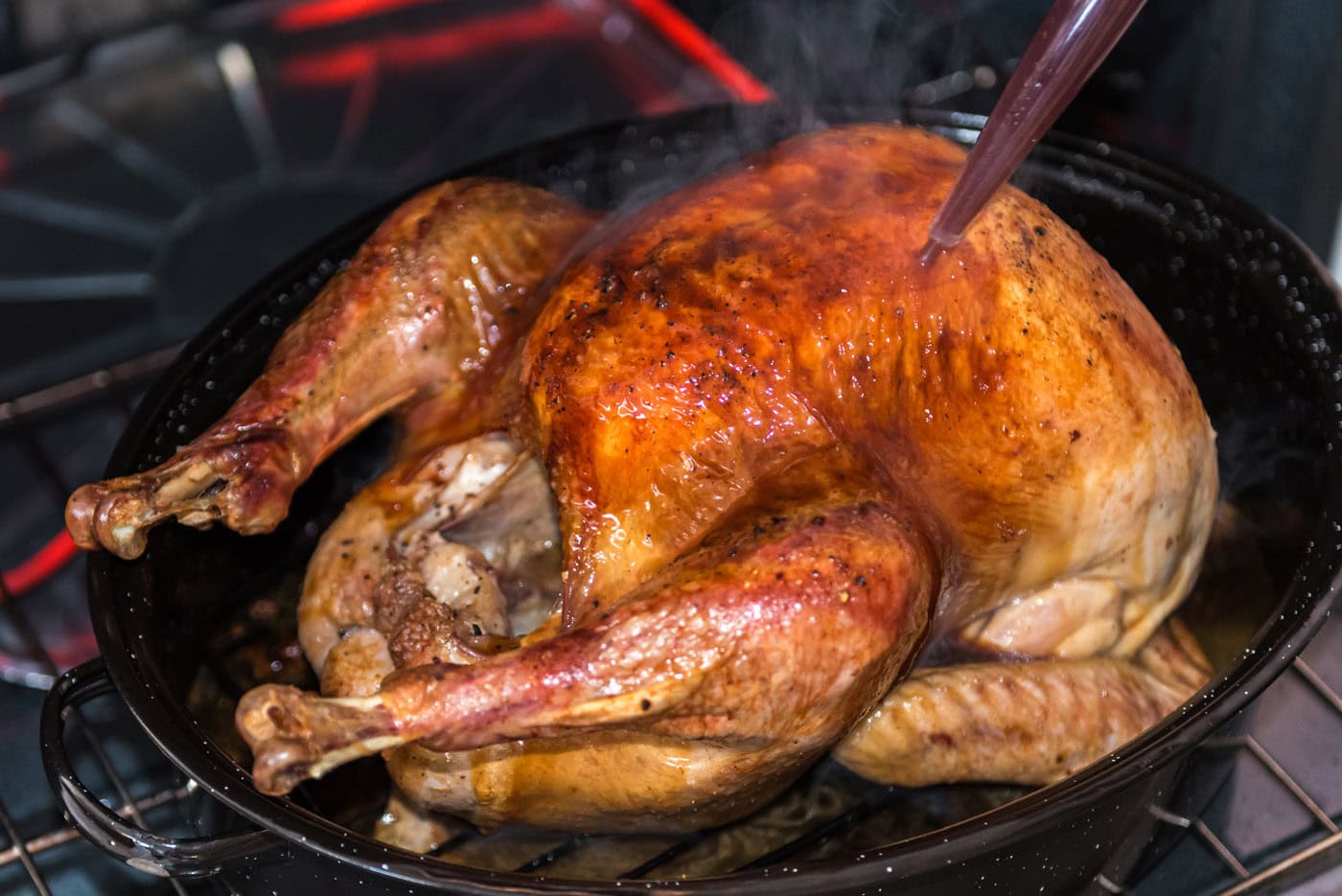 basting turkey with the pan juices in the oven