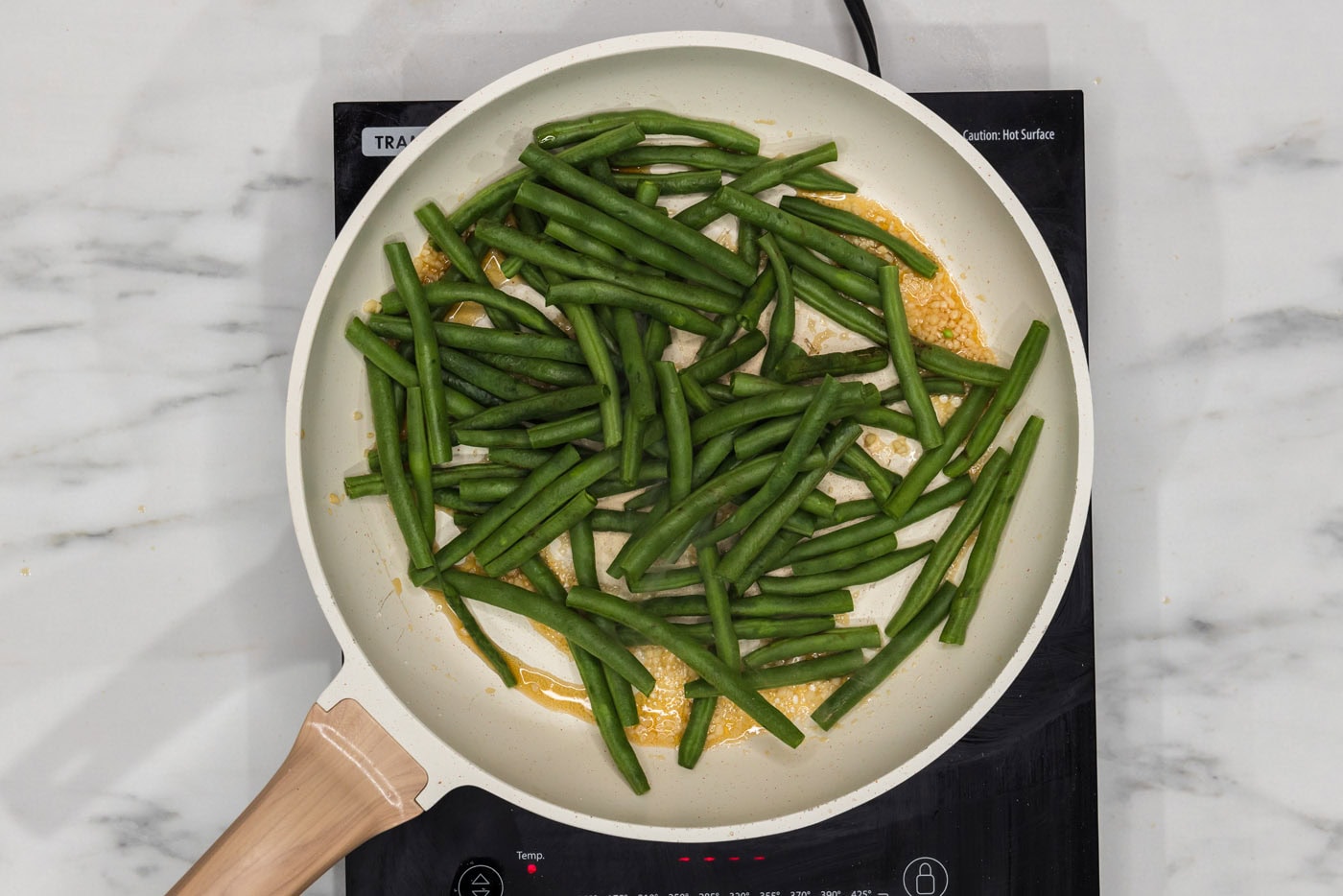 green beans in a skillet with garlic and sesame oil