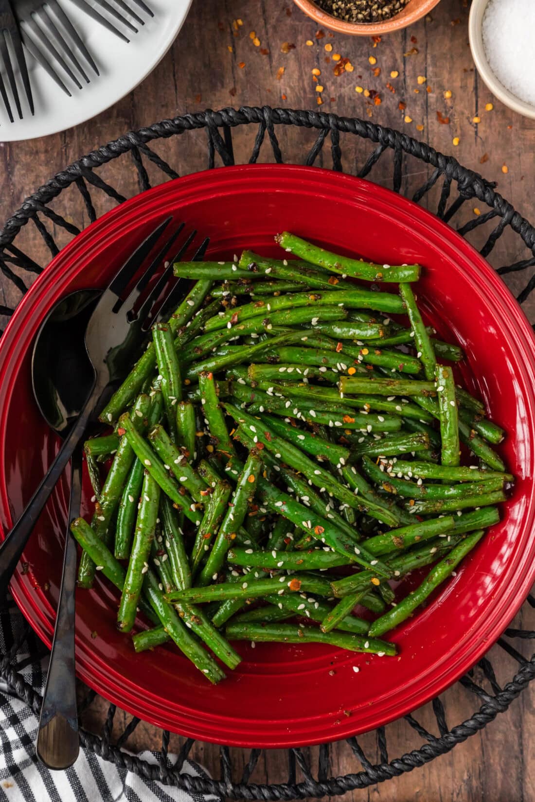 Sautéed Green Beans on a red plate with a serving fork and spoon resting to the side