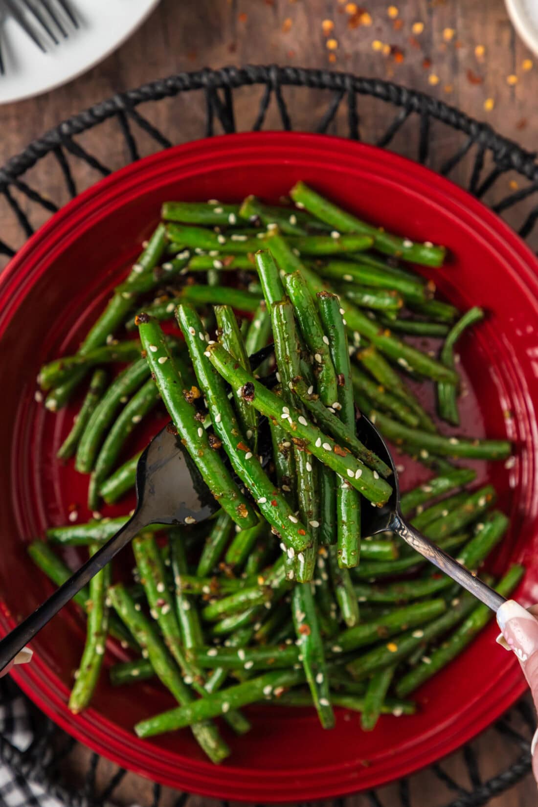 Serving utensils holding up Sautéed Green Beans above a plate