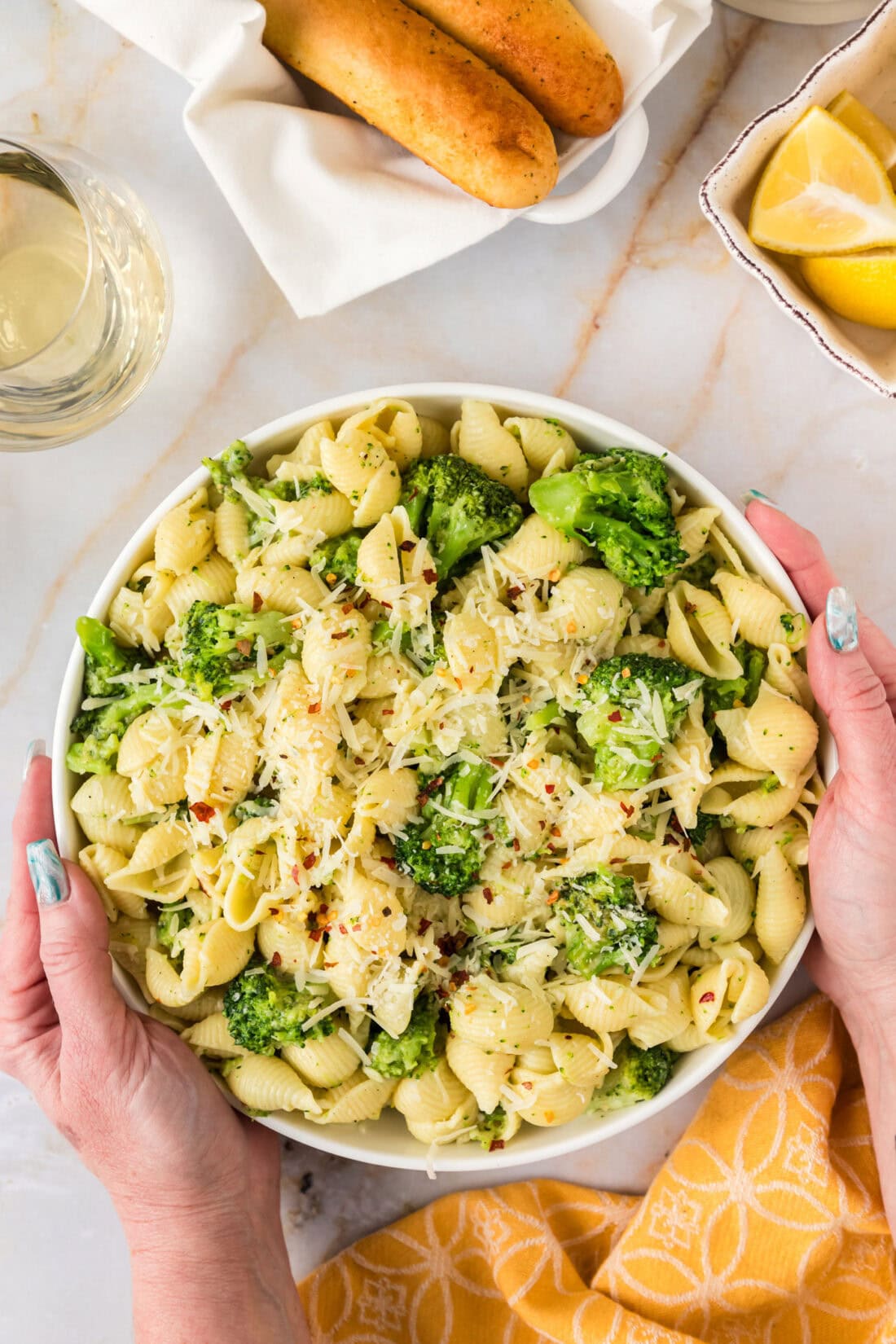 Hands holding a bowl of Broccoli Pasta