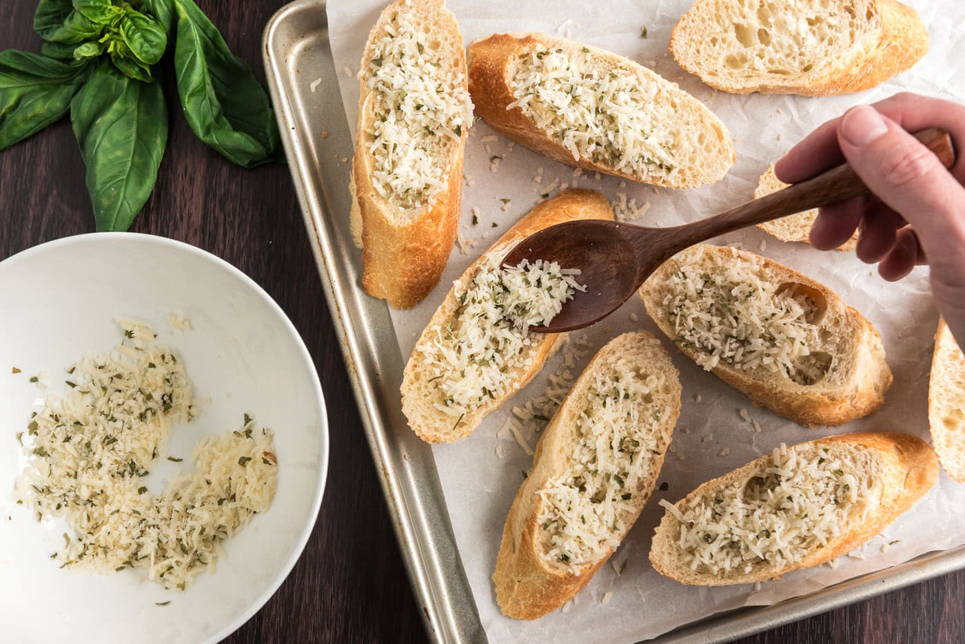 sprinkling parmesan and herbs over sliced bread