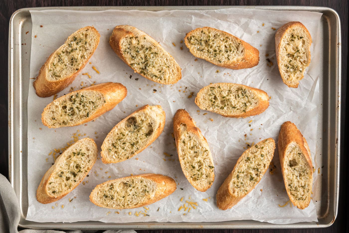 toasted bruschetta bread on a baking sheet with parmesan cheese