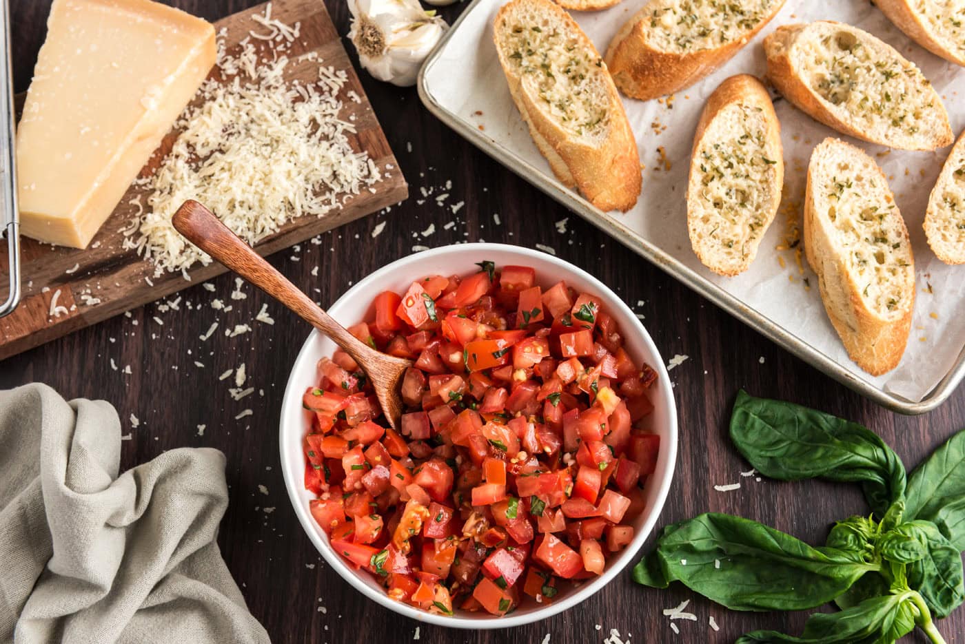 bruschetta tomato mixture in a bowl next to sliced bread with parmesan cheese