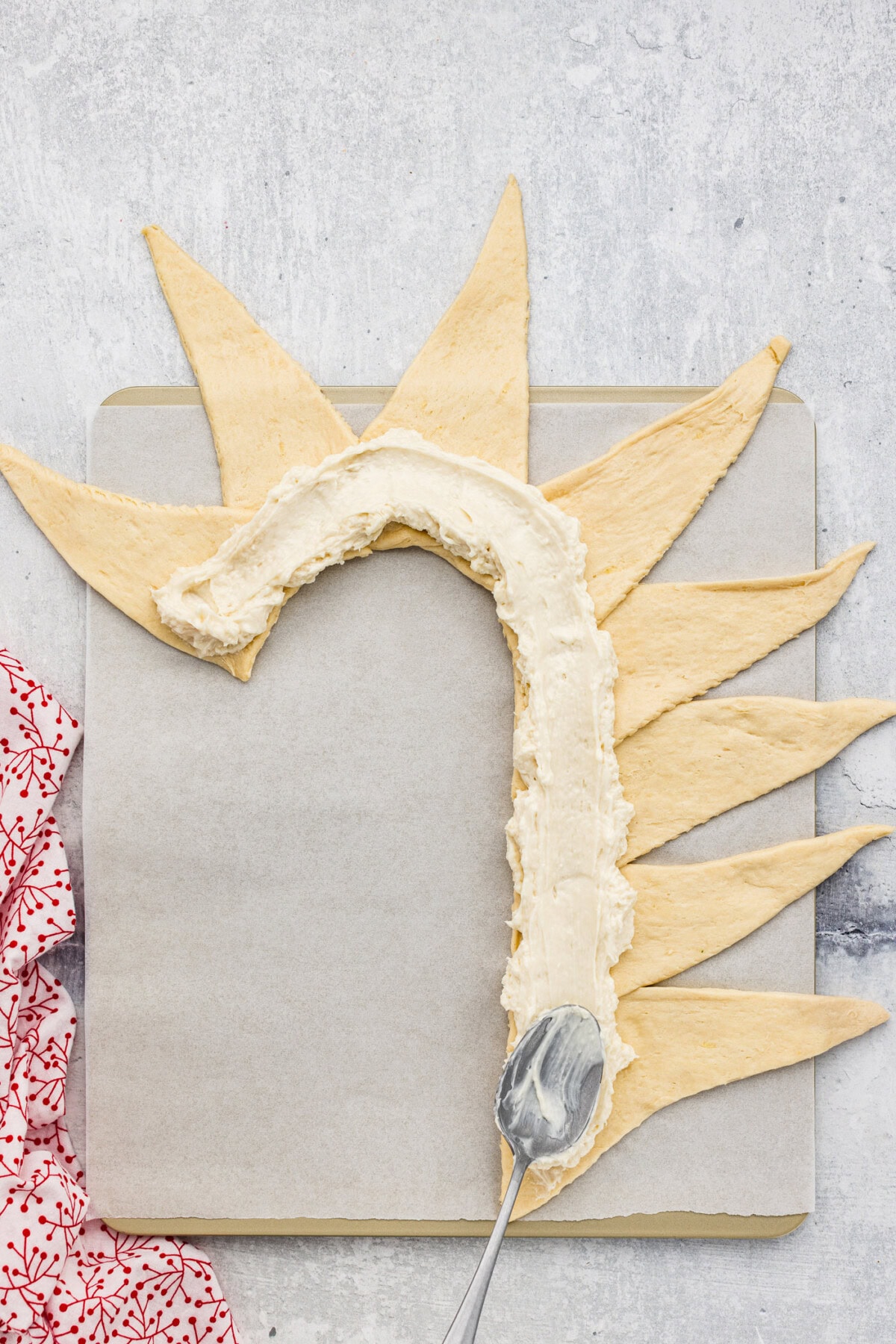 spreading cream cheese filling inside crescent roll dough