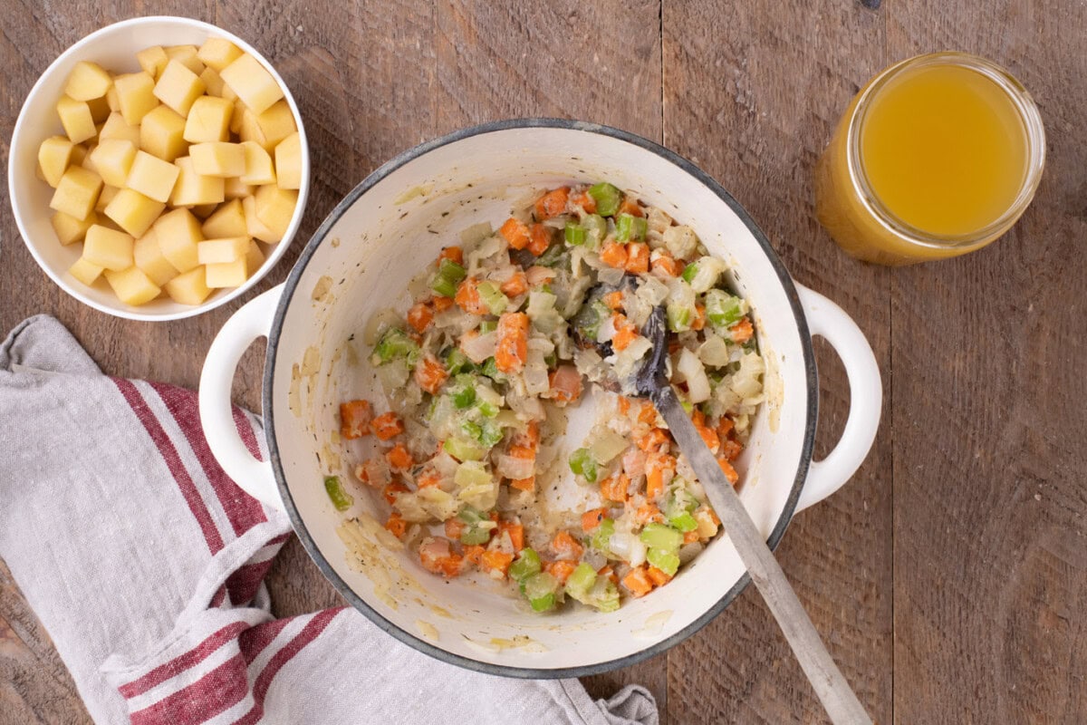 mixing vegetables with flour in a Dutch oven