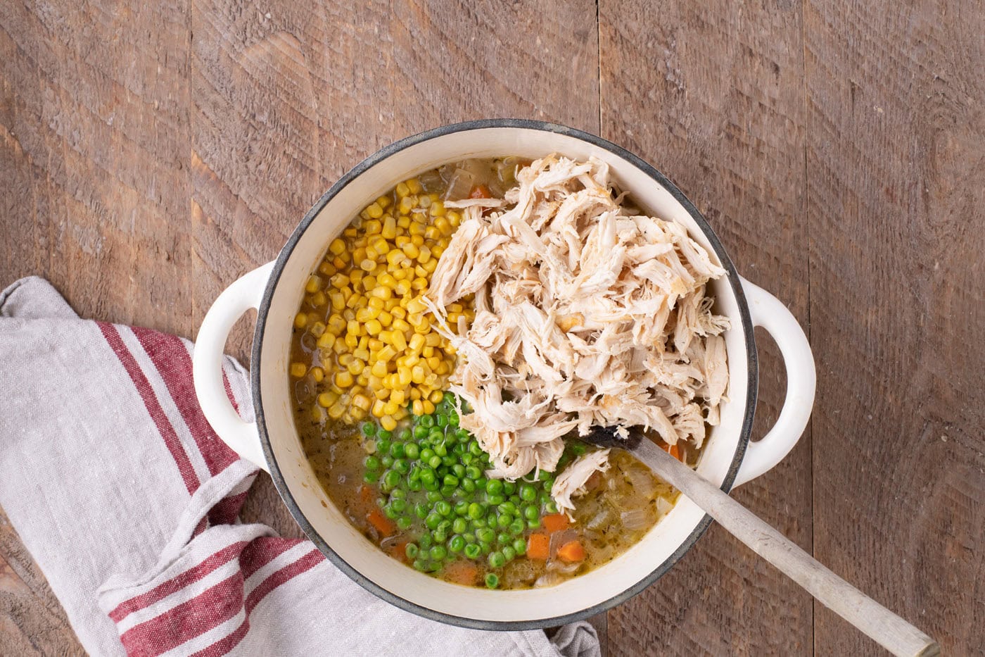 chicken, peas, and corn added to soup in a Dutch oven