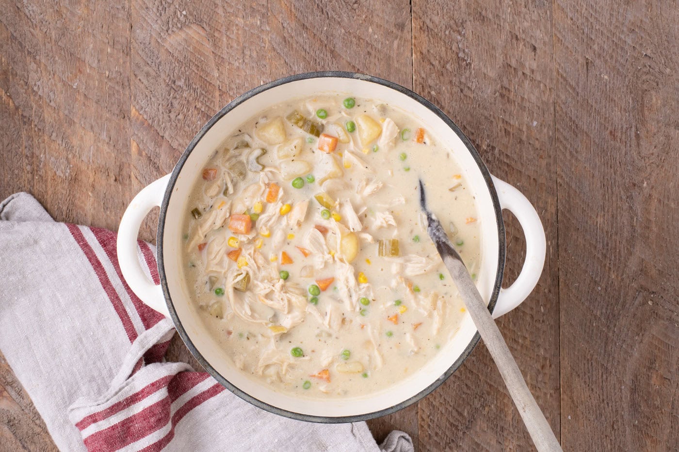 overhead of chicken pot pie soup in a Dutch oven with a spoon