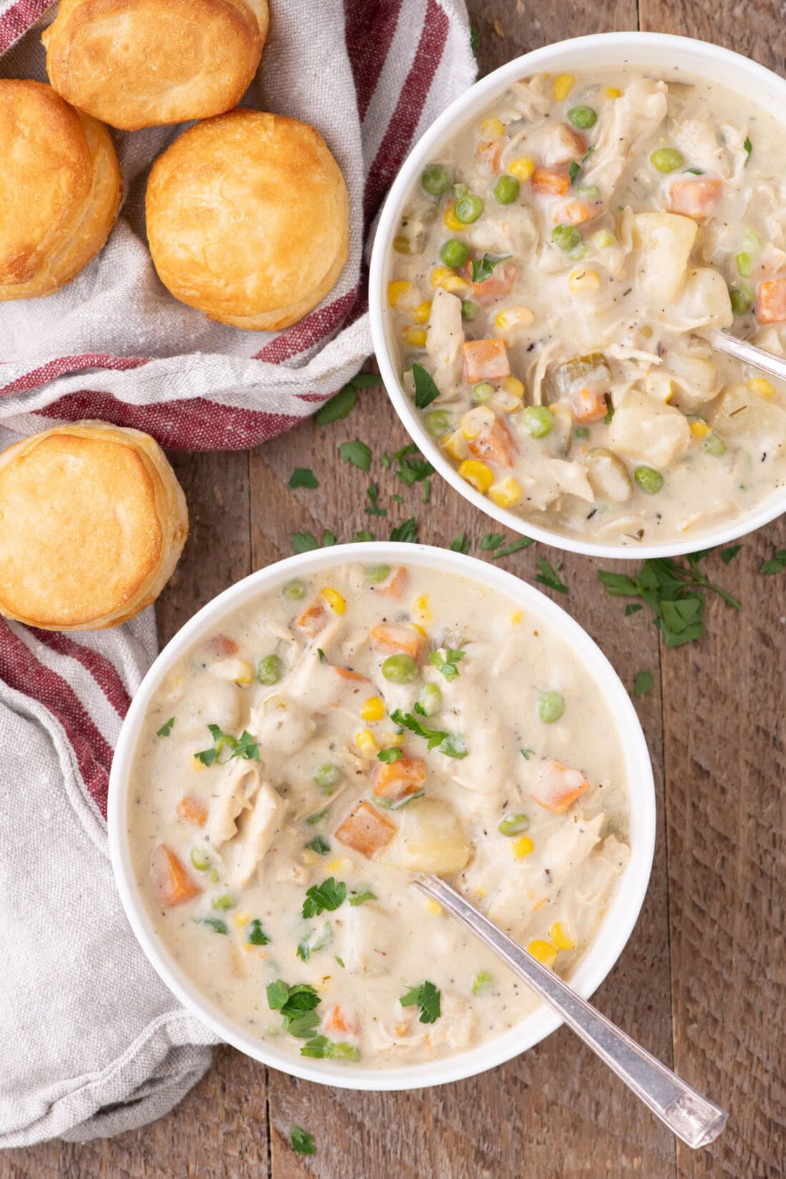 Two bowls of Chicken Pot Pie Soup with biscuits on the side