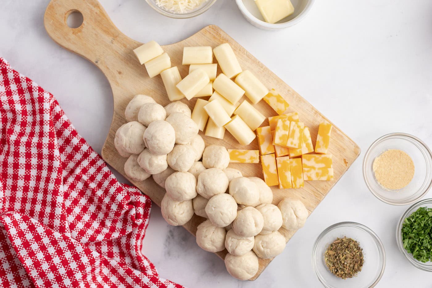 Cut up cheese sticks and biscuits rolled into balls on a wooden board