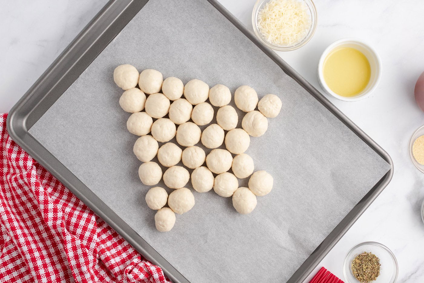 Biscuit balls on a parchment lined baking sheet int he shape of a tree