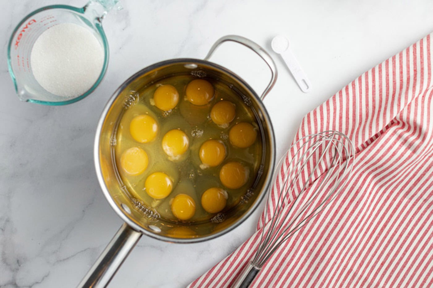 Saucepan of eggs with sugar and salt next to it