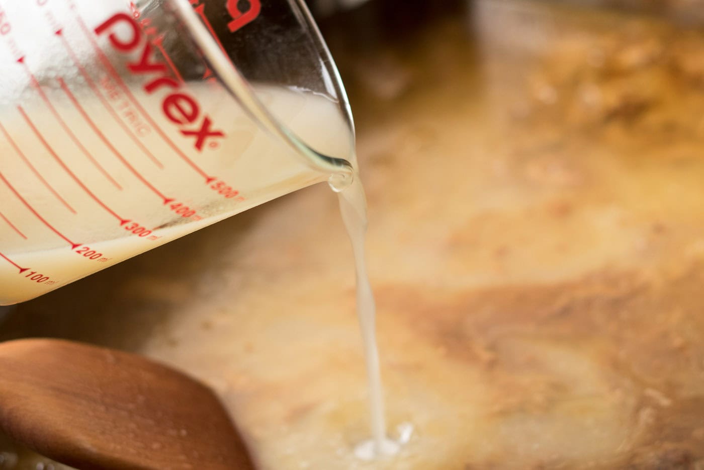 Broth being poured into a roasting pan