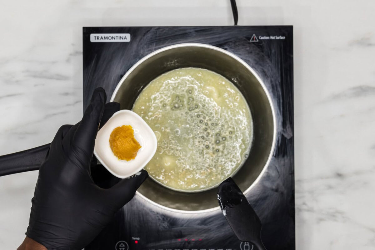 hand holding chicken base over melted butter in a saucepan