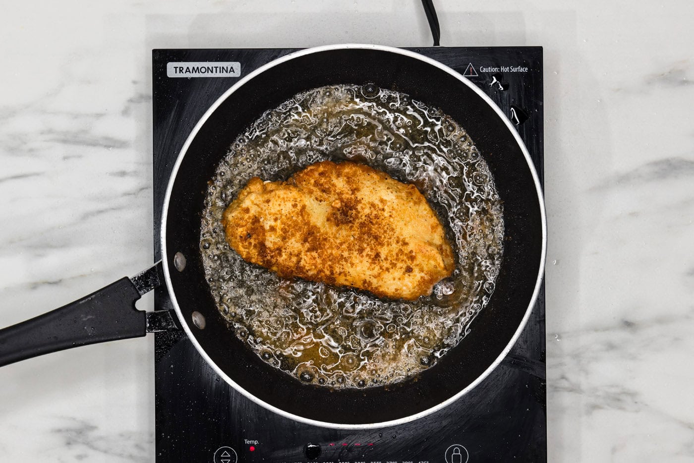 pan fried lemon chicken breast in a skillet of oil