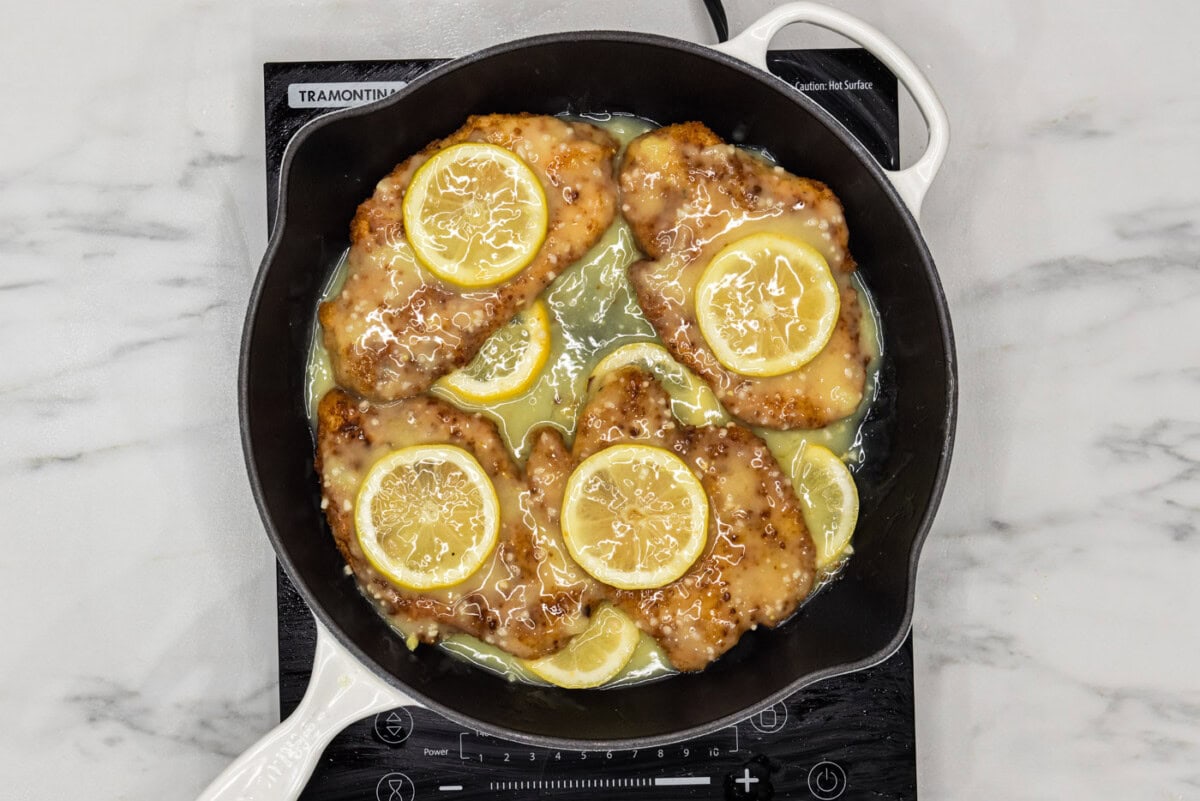 fried lemon chicken breasts in a pan of lemon garlic butter sauce