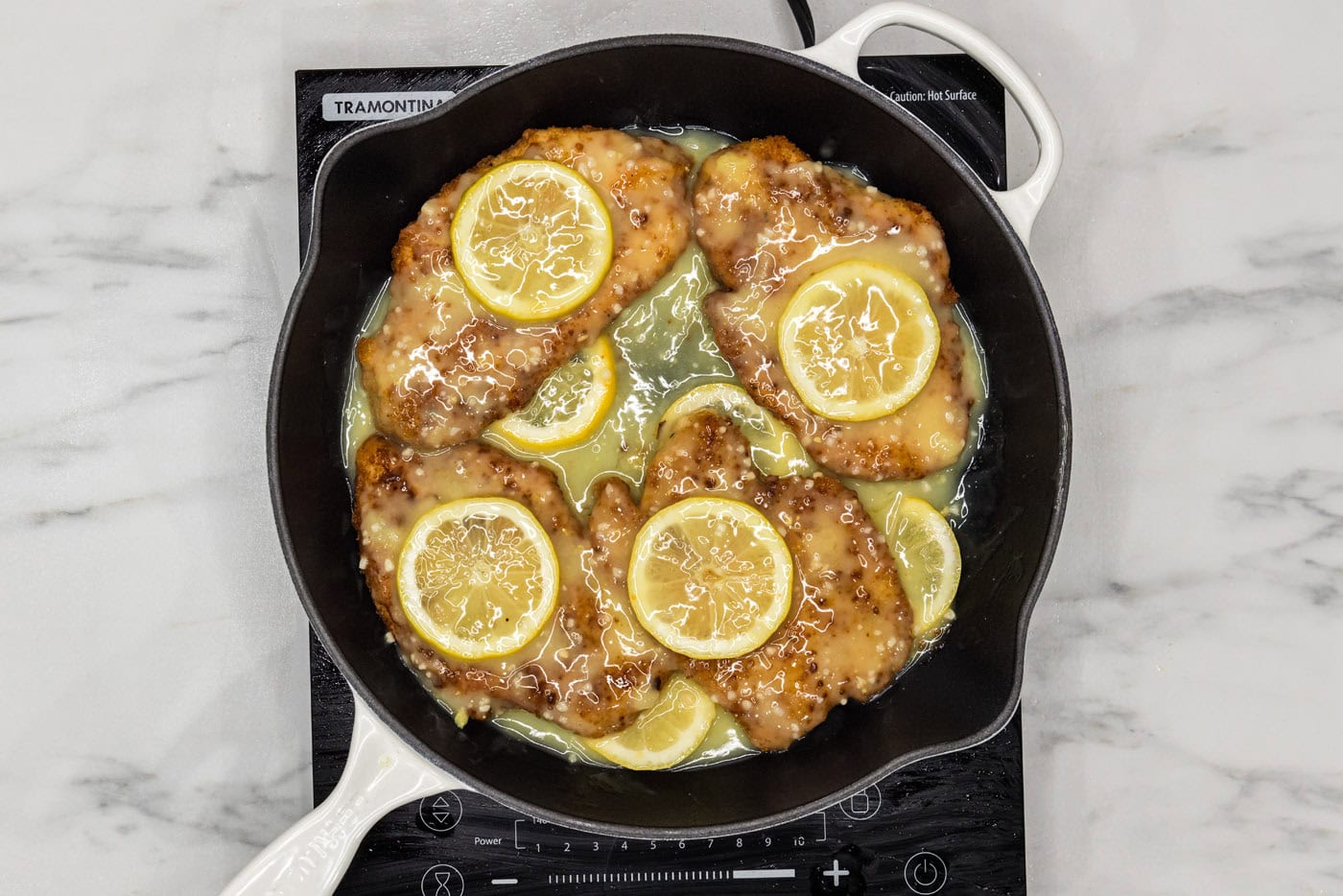 fried lemon chicken breasts in a pan of lemon garlic butter sauce