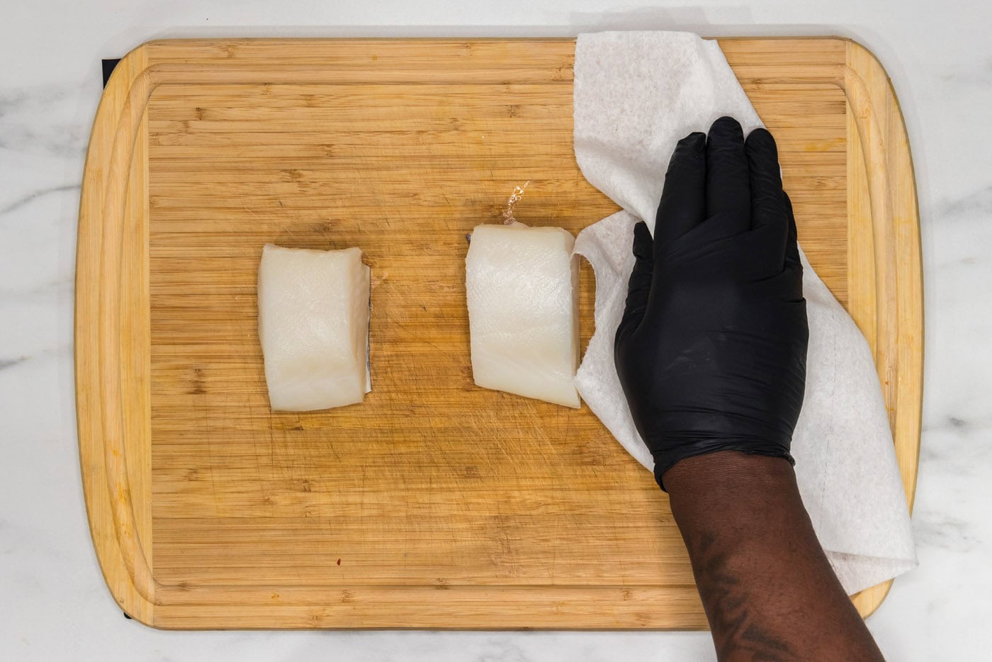 hand patting chilean sea bass dry with paper towels