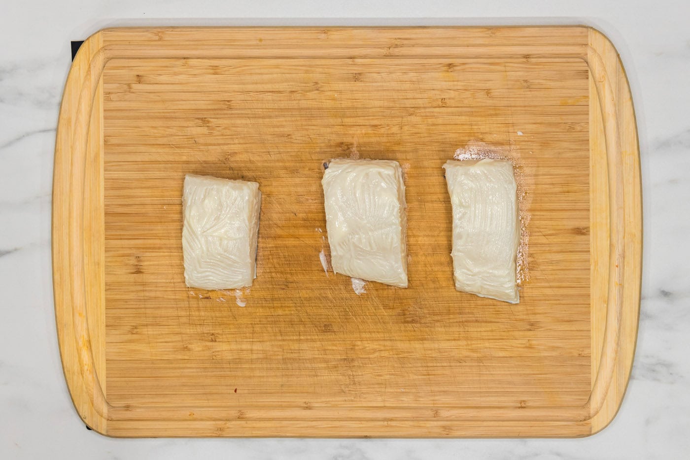 chilean sea bass brushed with butter on a cutting board