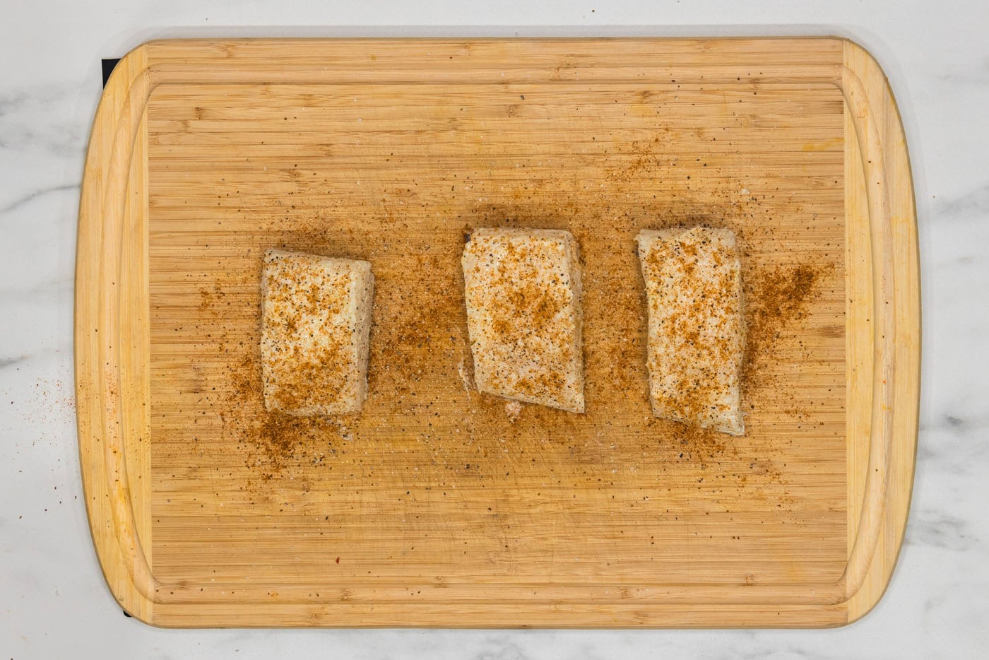 seasoned chilean sea bass filets on a cutting board