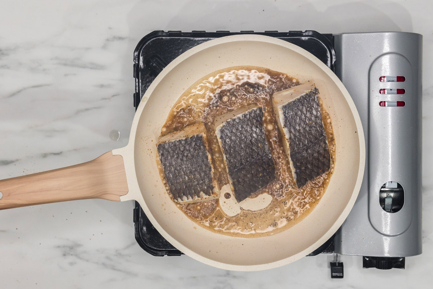 chilean sea bass filets cooking in a skillet skin side up