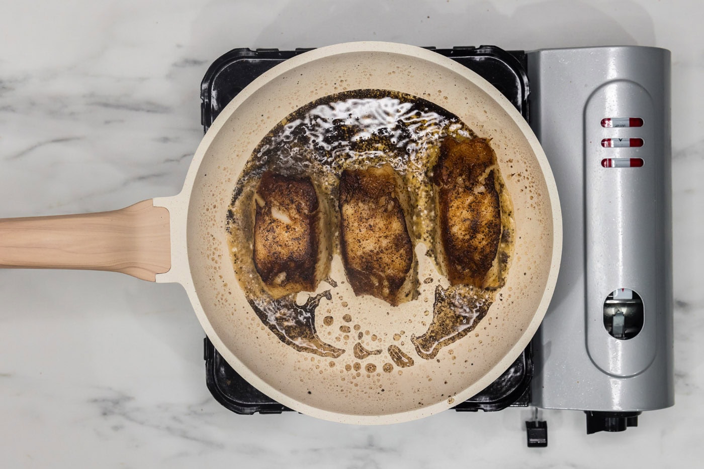 pan seared Chilean sea bass cooking in a skillet