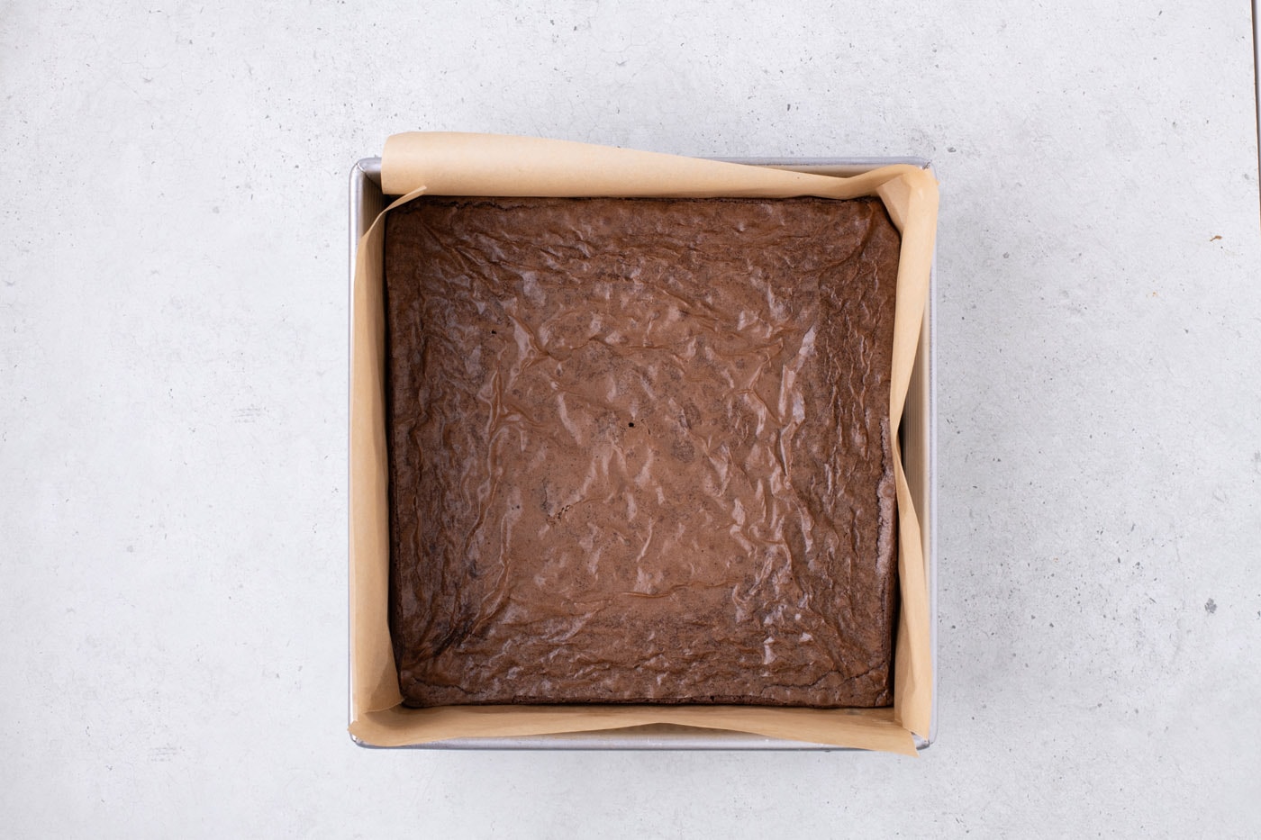 baked brownies in a parchment lined baking pan