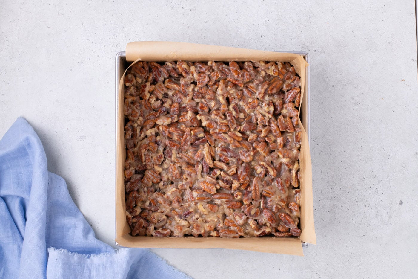 pecan pie topping on top of brownies in a baking pan