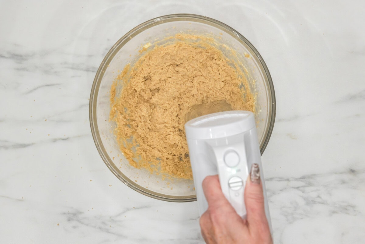 hand mixer combining brown sugar with creamed butter in a bowl