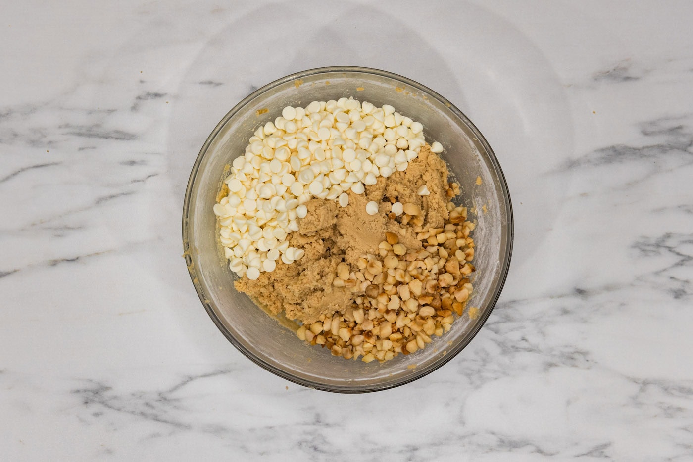 white chocolate chips and macadamia nuts added to bowl with cookie dough