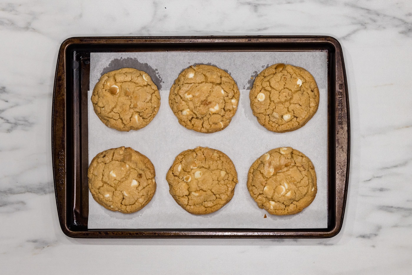 baked white chocolate macadamia nut cookies on a baking sheet