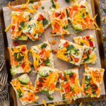 Slices of Appetizer Veggie Pizza on a parchment paper lined board