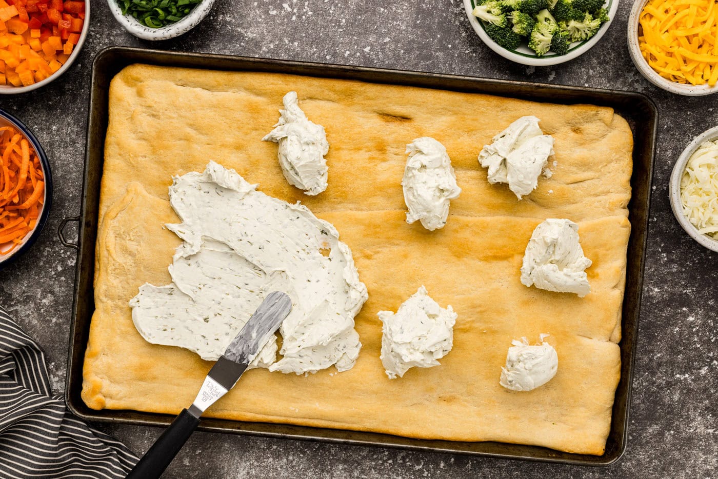 spreading cream cheese on baked crescent dough