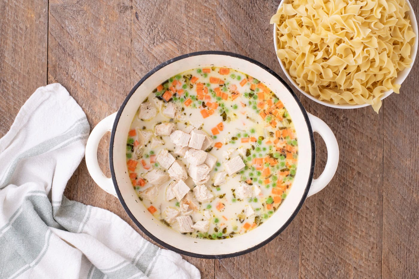 cubed chicken added to pot pie pasta in a pot