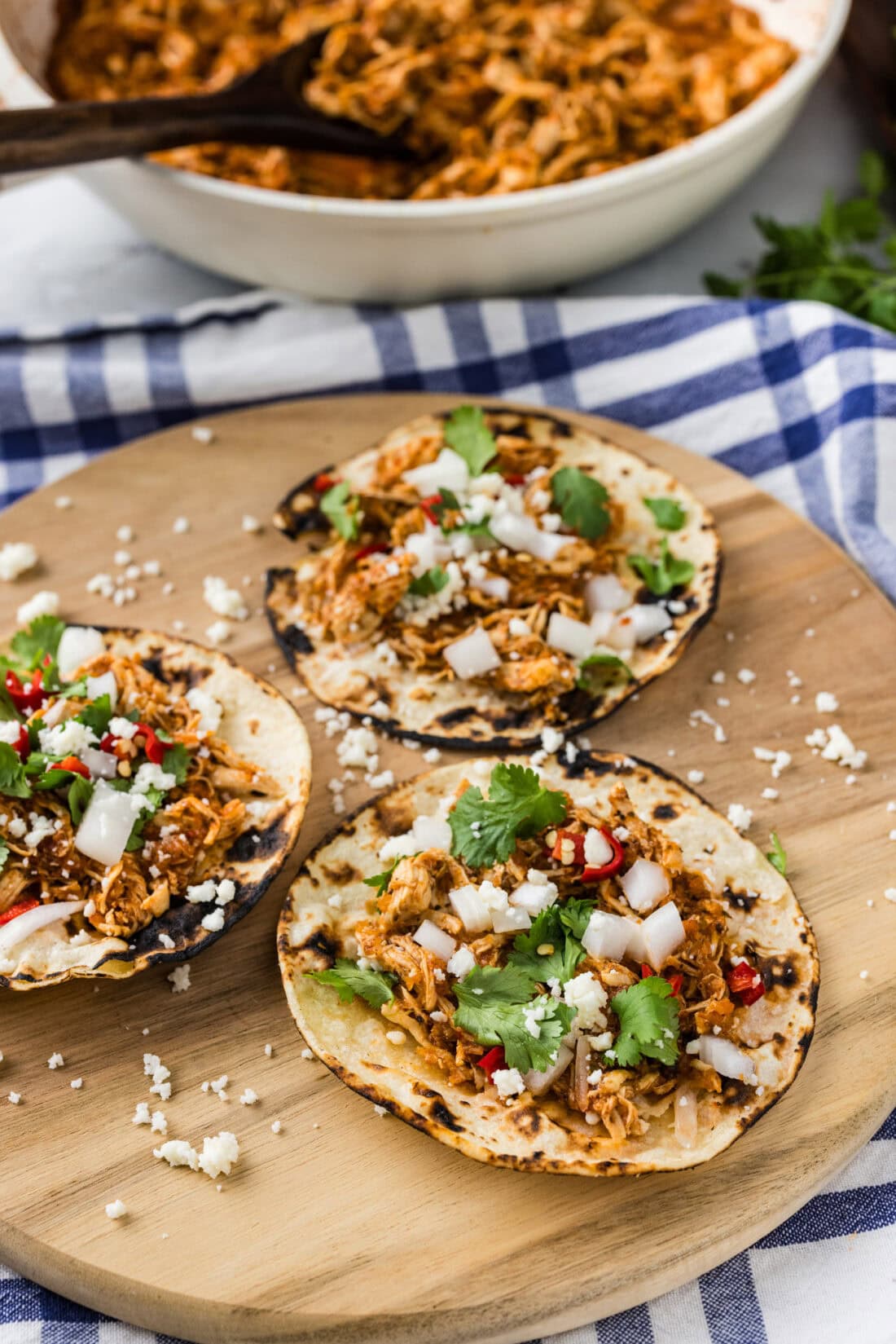 Three tortillas of Chicken Tinga topped with cilantro, onions and cheese