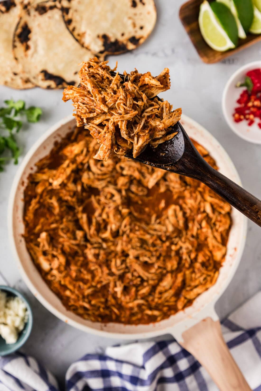 Spoonful of Chicken Tinga held above a skillet full of Chicken Tinga