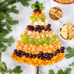 Christmas Tree Cheese Platter surrounded by crackers and Christmas tree branches