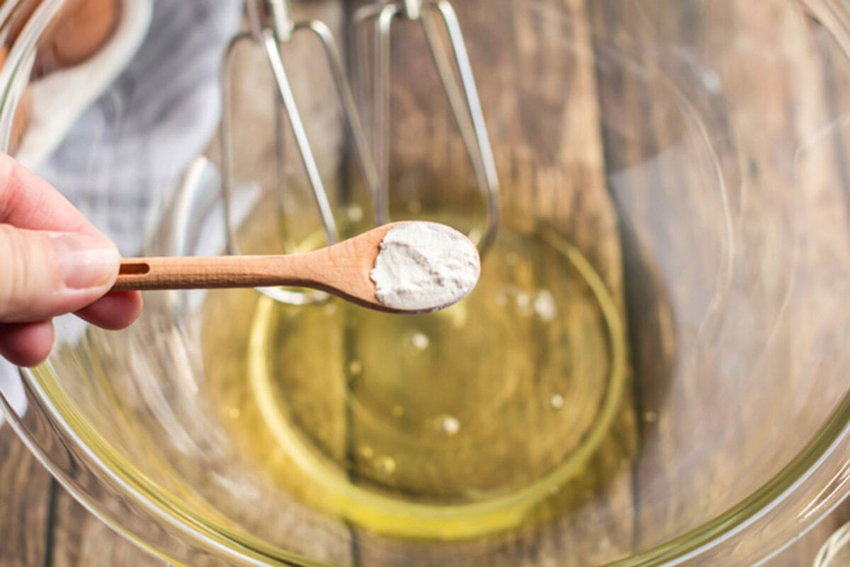 Cream of tartar being added into a bowl of egg whites