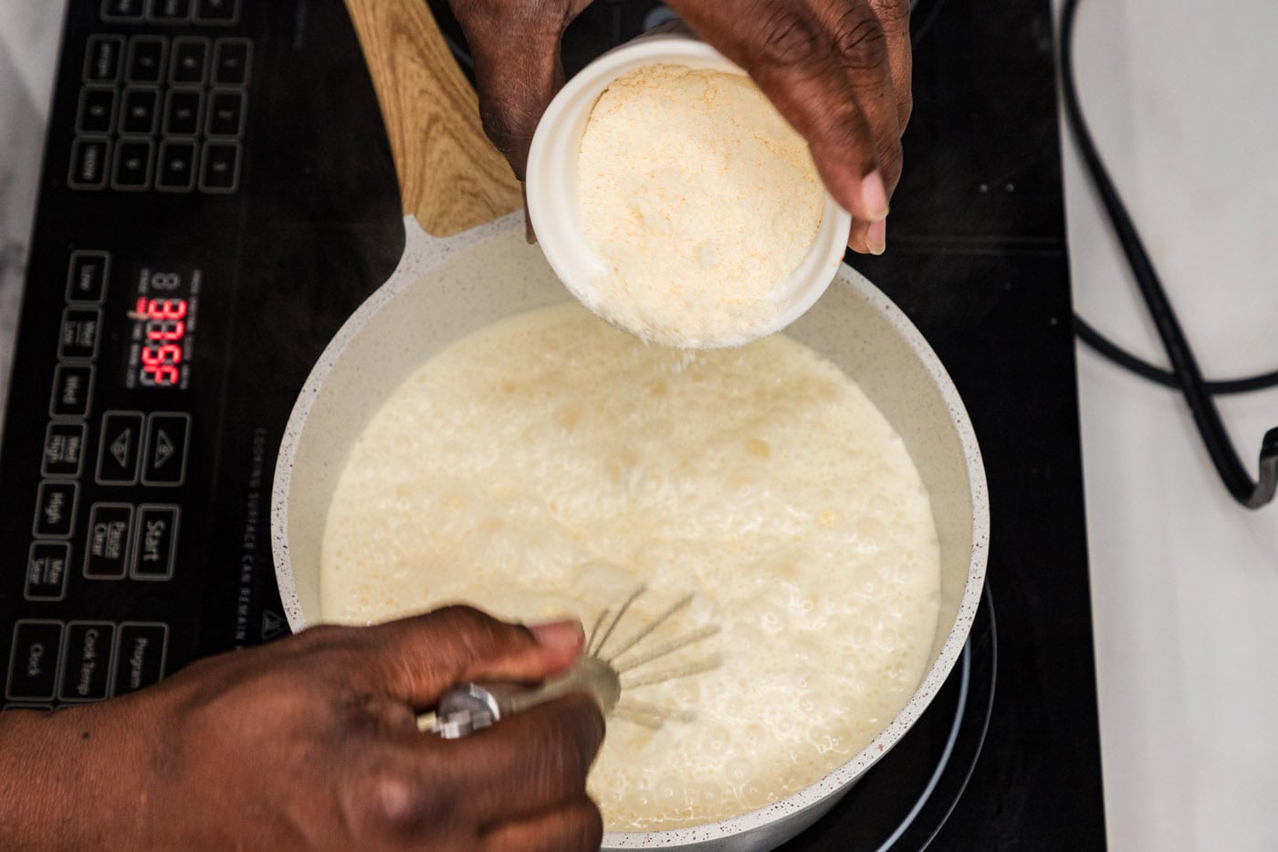 whisking parmesan cheese into cream and wine sauce in a skillet