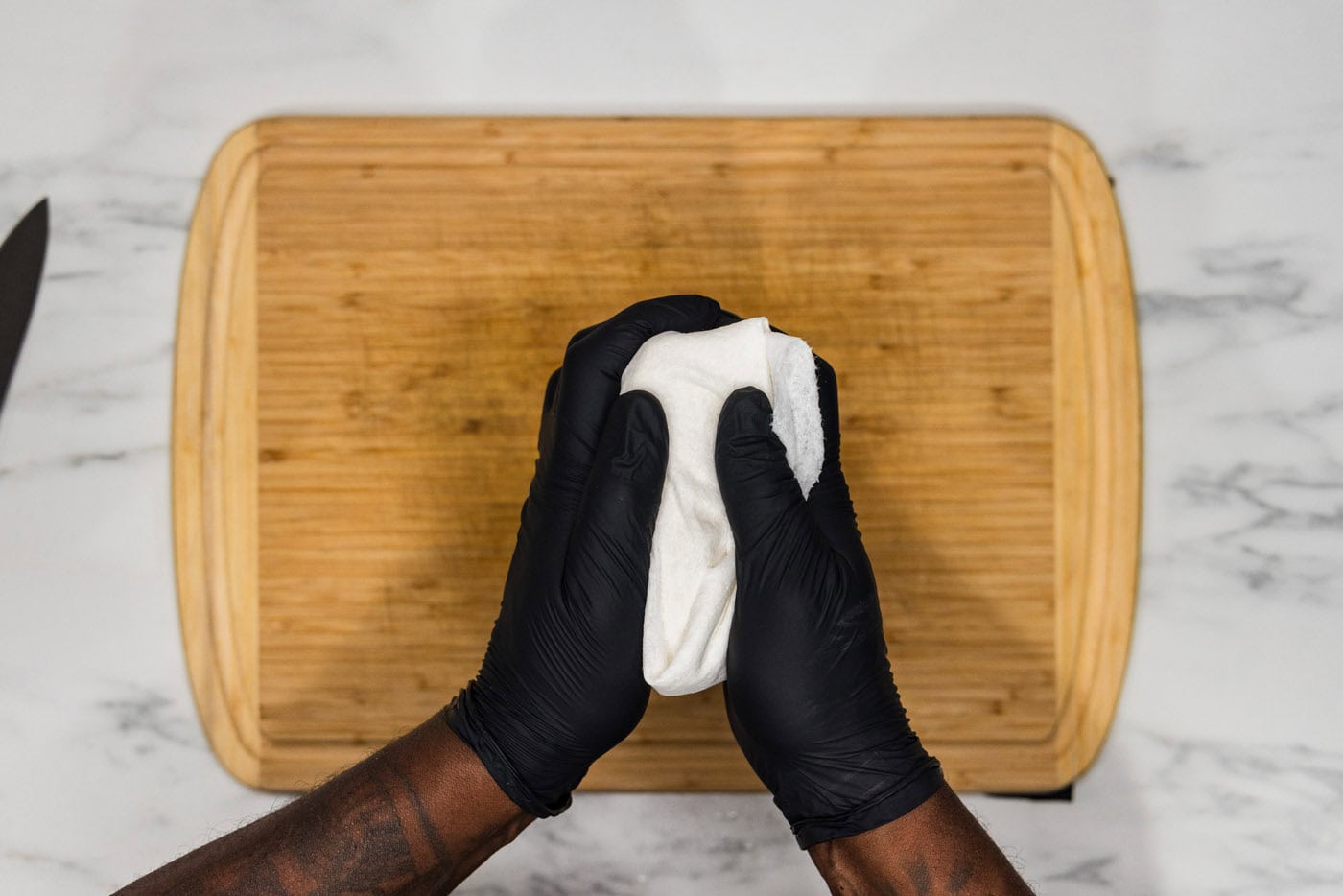 hands squeezing tofu in paper towels