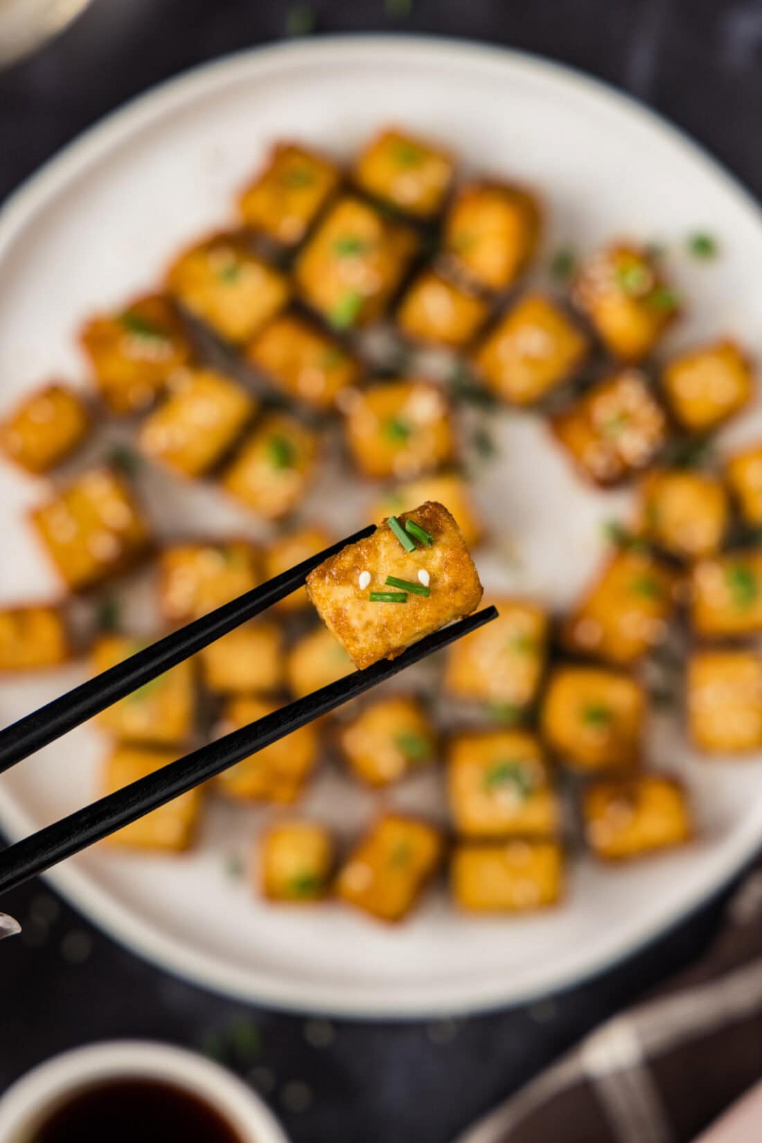 Chopsticks holding up a piece of Fried Tofu