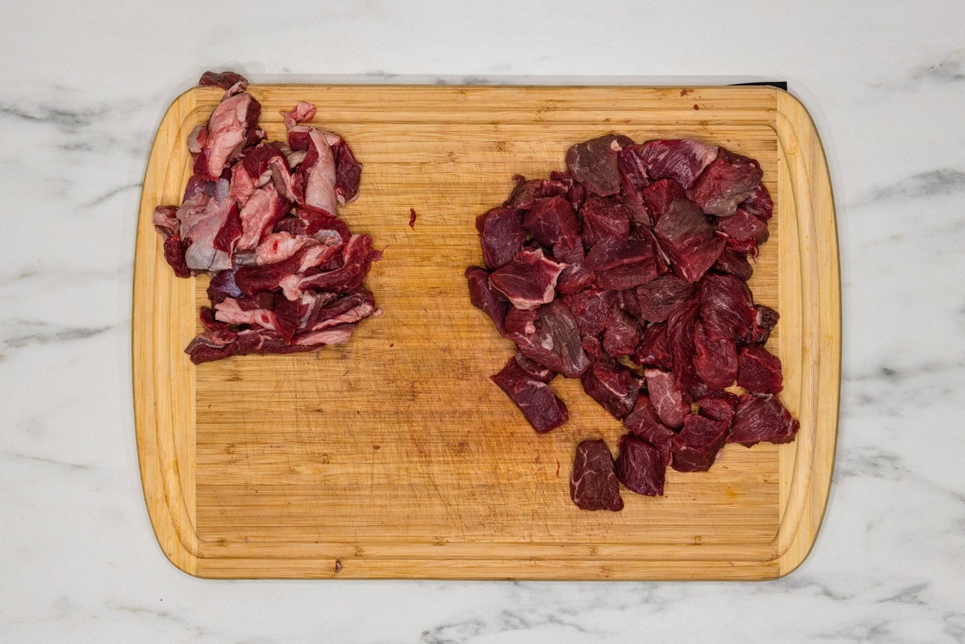 cubed steak on a cutting board with fat trimmed off